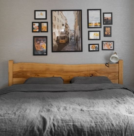 Stylish bedroom with wooden headboard and gallery wall art, representing property management and rentals services.